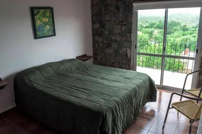 a bedroom with a green bed and a balcony at Cabañas Alma de Pueblo, Mayu Sumaj in San Antonio de Arredondo