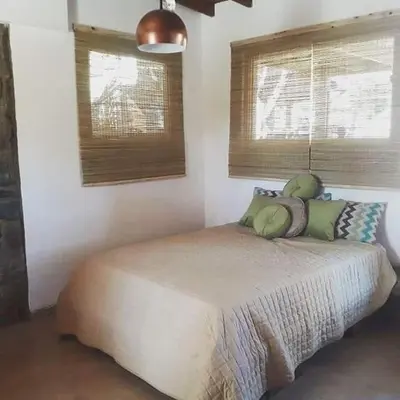 a bedroom with a bed with two pillows and two windows at Altos del Molle SF in San Francisco del Monte de Oro