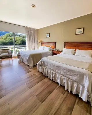 a hotel room with two beds and a large window at Howard Johnson Hotel & Spa Villa General Belgrano in Villa General Belgrano