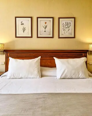 a bed with white pillows and three pictures on the wall at Howard Johnson Hotel & Spa Villa General Belgrano in Villa General Belgrano