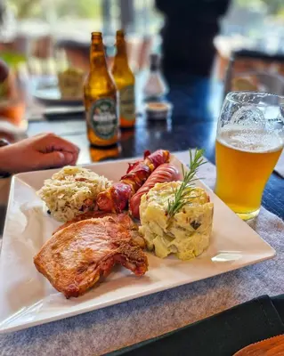 a plate of food on a table with a glass of beer at Howard Johnson Hotel & Spa Villa General Belgrano in Villa General Belgrano