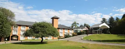 a large building with a tree in front of it at Howard Johnson Hotel & Spa Villa General Belgrano in Villa General Belgrano