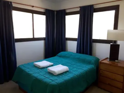 a bedroom with a green bed with two towels on it at Casa en La Cumbrecita in La Cumbrecita