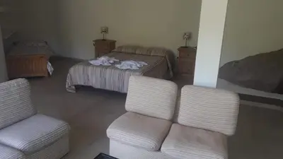 a bedroom with a bed and two chairs and a couch at Casa en La Cumbrecita in La Cumbrecita
