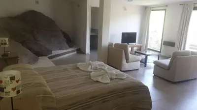 a bedroom with a bed and two chairs and a television at Casa en La Cumbrecita in La Cumbrecita