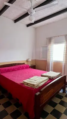 a bedroom with a bed with a red bedspread and a window at Casa en el centro in Villa Cura Brochero