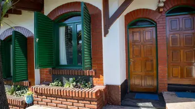 a house with green shutters and two doors at Bungalows Punta Azul in Villa Carlos Paz