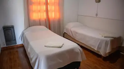 two beds in a room with white sheets at Bungalows Punta Azul in Villa Carlos Paz