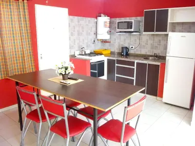 a kitchen with a wooden table with red chairs at Los Ceibos in Villa Carlos Paz