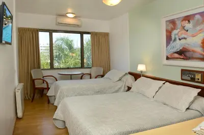 a hotel room with two beds and a table at Hotel Capvio in Villa Carlos Paz
