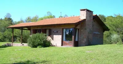 a small brick house with a door in a field at El Rodeo Apart Cabañas in Santa Rosa de Calamuchita