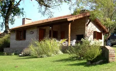 a small house in a yard with a car parked at El Rodeo Apart Cabañas in Santa Rosa de Calamuchita