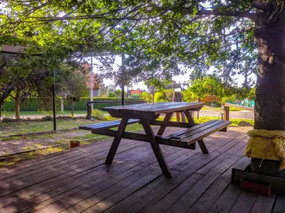 a picnic table sitting on a wooden deck under a tree at La Casita Alquiler Temporario in Merlo