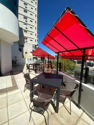 a group of tables and chairs with red umbrellas on a roof at Apart Riviera Tower Suites in Villa Carlos Paz