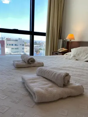 a bedroom with towels on a bed with a large window at Apart Riviera Tower Suites in Villa Carlos Paz