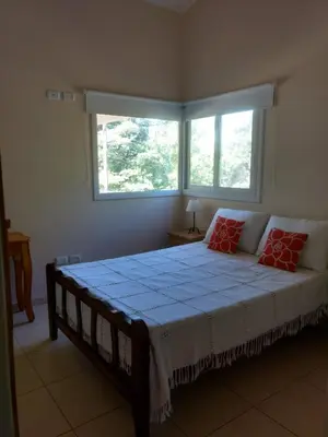 a bedroom with a large bed with two red pillows at Casa en Villa Los Aromos in La Bolsa