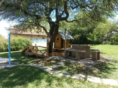 a playground under a tree with a house at Casa en Villa Los Aromos in La Bolsa