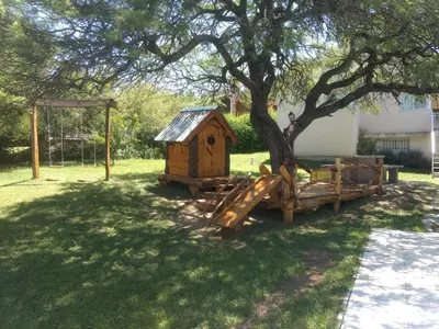 a wooden play house under a tree in a yard at Casa en Villa Los Aromos in La Bolsa
