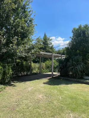 a wooden pergola in a yard with trees and grass at La Elina in Villa General Belgrano