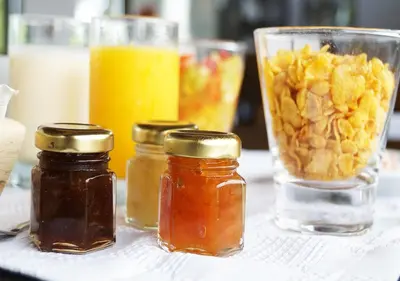 a table with four jars of honey and a glass of orange juice at A Hotel Decosuites in Merlo