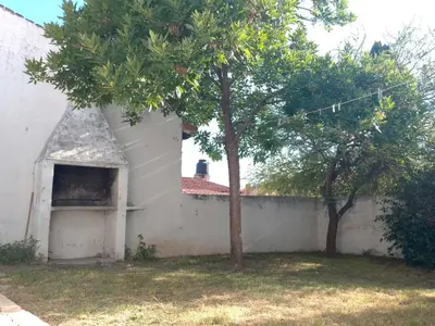 a white building with a tree in the yard at Casa Monty in Mina Clavero