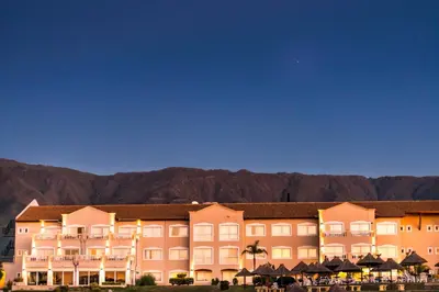 a large hotel with mountains in the background at Howard Johnson Resort Spa & Convention Center in Merlo