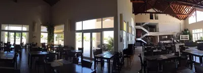 a restaurant with tables and chairs and large windows at Howard Johnson Resort Spa & Convention Center in Merlo
