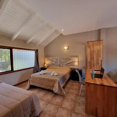a hotel room with two beds and a desk at Apartamentos Andrea in Villa General Belgrano