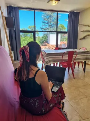 a woman sitting on a couch using a laptop at Apartamentos Andrea in Villa General Belgrano