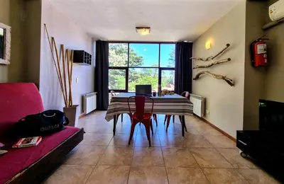 a living room with a table with chairs and a large window at Apartamentos Andrea in Villa General Belgrano