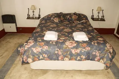 a bed with a floral comforter in a bedroom at Rancho La Peregrina in Nono