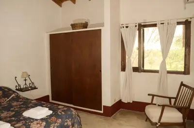 a bedroom with a bed and a chair and a window at Rancho La Peregrina in Nono