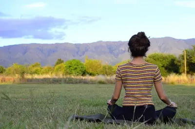 a woman is sitting in a field doing meditation at Rancho La Peregrina in Nono