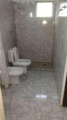 a bathroom with a toilet and a shower with a window at La Casa de Patis in Villa Carlos Paz