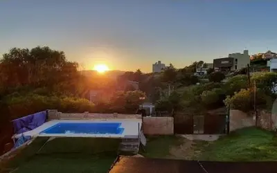 a pool in a yard with the sunset in the background at La Casa de Patis in Villa Carlos Paz