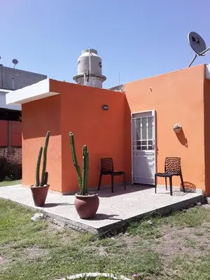 a building with two chairs and two cactuses in front of it at Casa de Silvia in Villa Carlos Paz