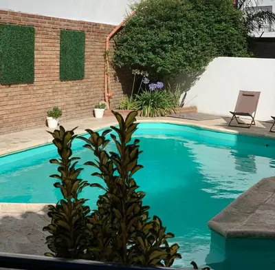 a blue swimming pool with a plant in the foreground at Ganesha in Villa Carlos Paz