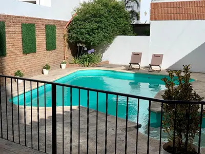 a swimming pool with two chairs next to a fence at Ganesha in Villa Carlos Paz