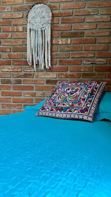 a bed with a pillow and a brick wall at Ganesha in Villa Carlos Paz