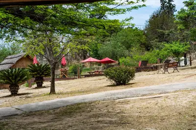 a park with picnic tables and red umbrellas at Capilla del Lago in Villa Carlos Paz