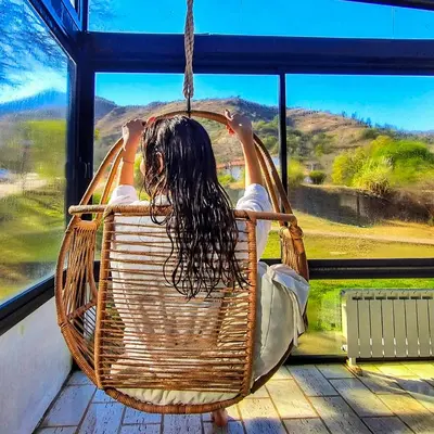 a woman sitting in a wicker chair looking out a window at Harmonie Hotel De Montaña - Adults only in Villa General Belgrano