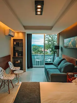 a living room with a green couch and a balcony at Pinares del Cerro Resort & Suites in Villa Carlos Paz
