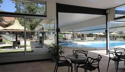 a patio with a table and chairs and a pool at Pinares del Cerro Resort & Suites in Villa Carlos Paz