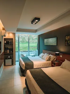 a hotel room with two beds and a balcony at Pinares del Cerro Resort & Suites in Villa Carlos Paz