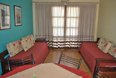 a living room with two red beds and a window at Apart Hotel El Portico in Villa Carlos Paz