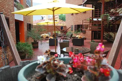 a patio with an umbrella and a table and chairs at Apart Hotel El Portico in Villa Carlos Paz
