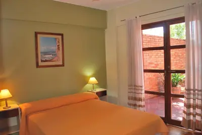 a bedroom with an orange bed and a window at Apart Hotel El Portico in Villa Carlos Paz