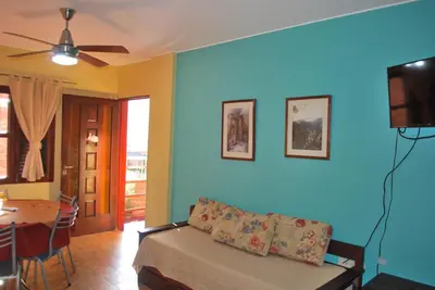 a living room with a couch and a tv and a table at Apart Hotel El Portico in Villa Carlos Paz