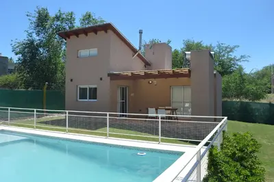 a villa with a swimming pool in front of a house at Kawsay Complejo de Cabañas in San Antonio de Arredondo