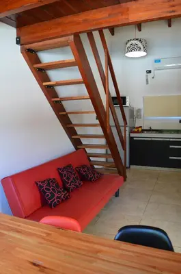 a red couch in a living room with a staircase at Kawsay Complejo de Cabañas in San Antonio de Arredondo